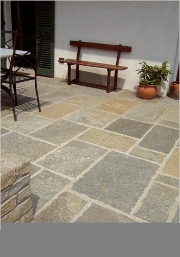 Una panca di legno si trova su un patio accanto a un tavolo e delle sedie