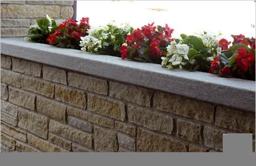 Un muro di mattoni con una fioriera piena di fiori rossi e bianchi