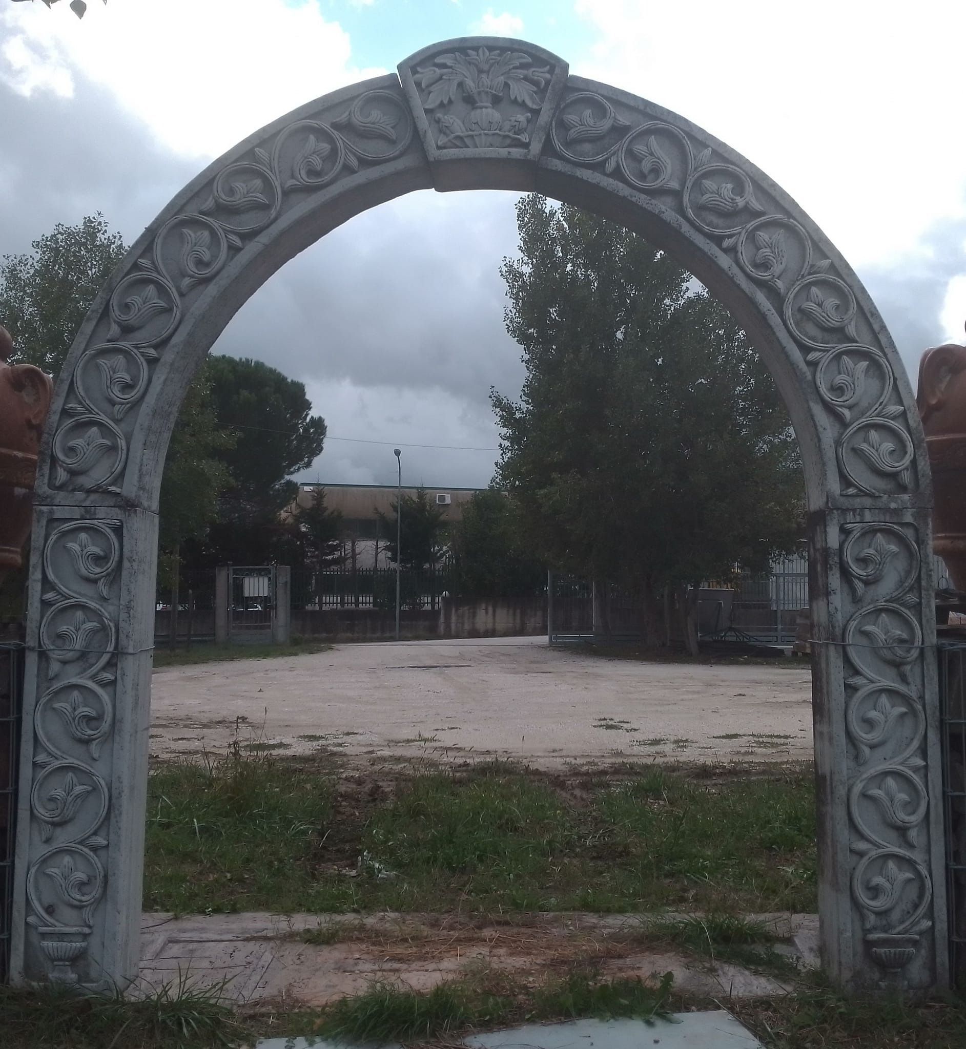 Un arco di pietra in un parco con alberi sullo sfondo