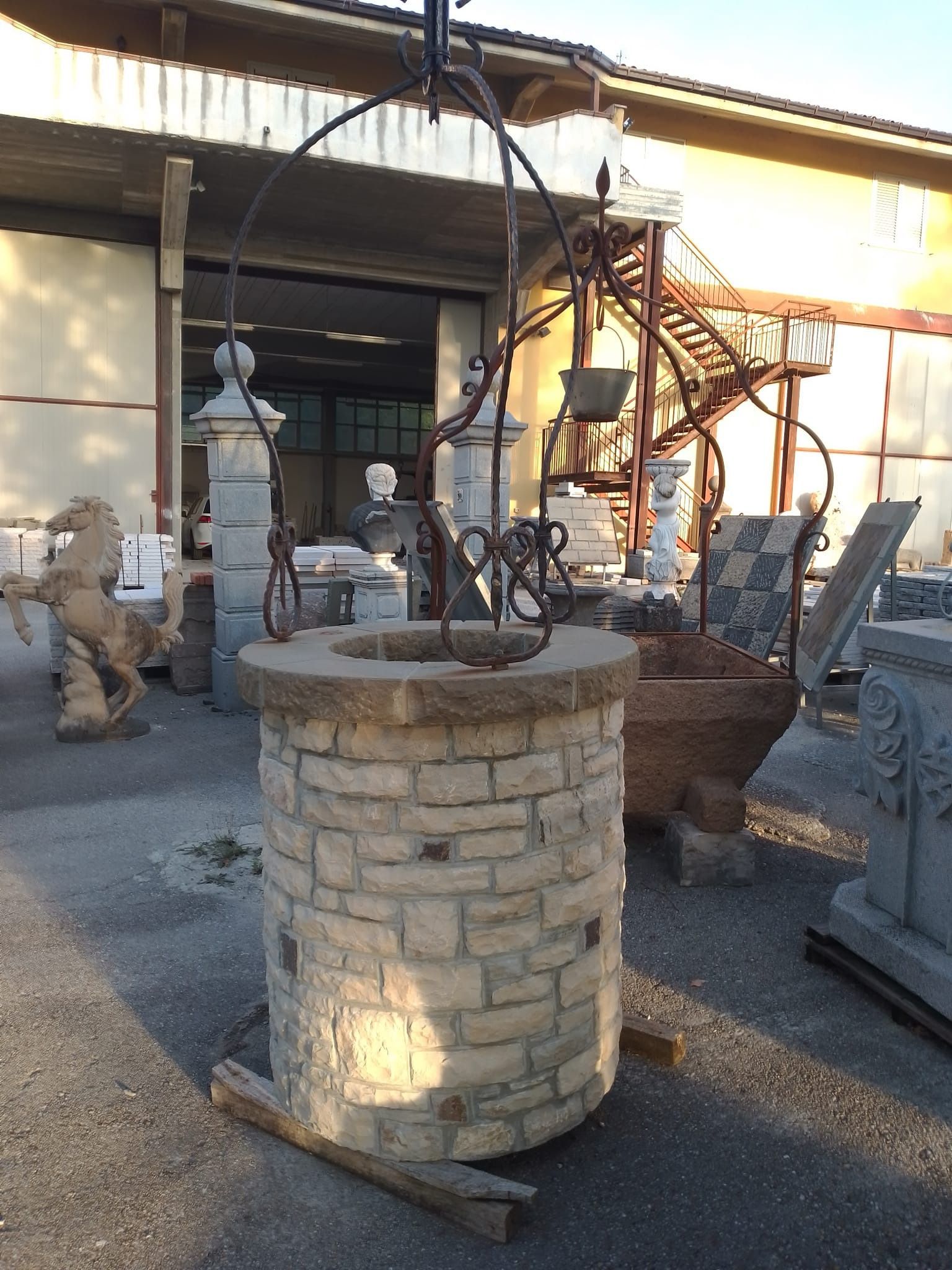 Di fronte a un edificio c'è un pozzo di pietra.