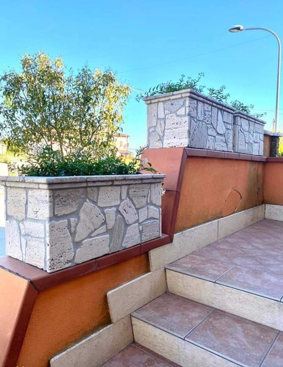 Una scalinata con un muro in pietra e fioriere ai lati.