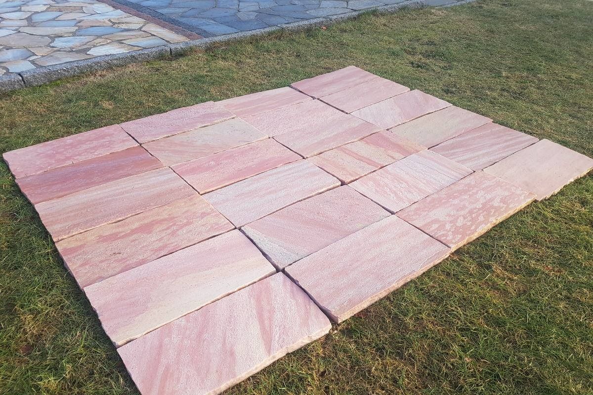Un mucchio di piastrelle rosa adagiate sopra un lussureggiante campo verde.