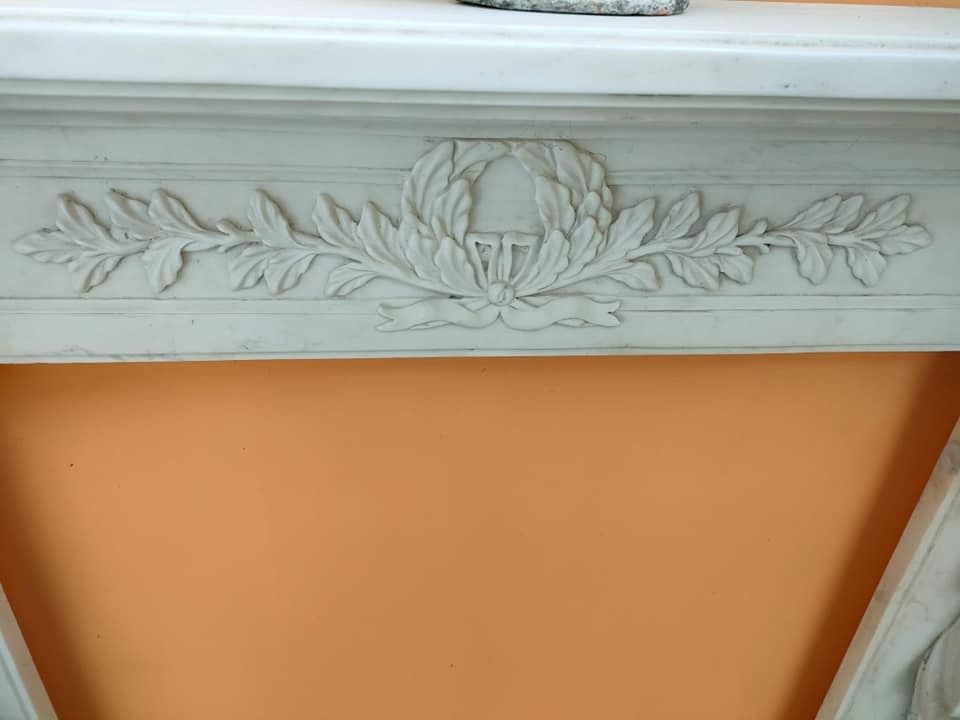 Una mensola per camino decorata con un disegno floreale è appoggiata su una parete arancione.