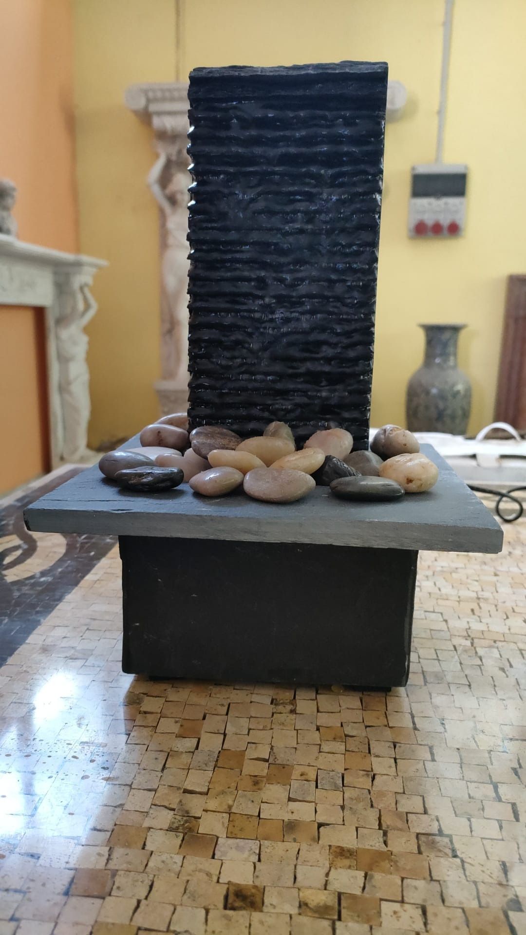 Una fontana d'acqua è posta sopra un tavolo con delle rocce.