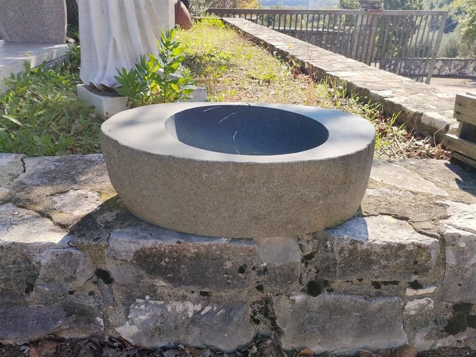 Una grande ciotola di pietra è posta in cima a un muro di pietra.