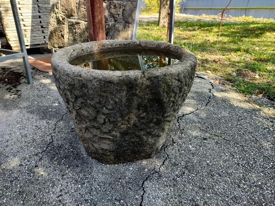 Sul terreno è appoggiato un grande vaso di pietra pieno d'acqua.