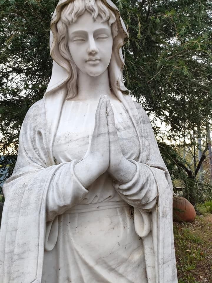 Una statua di una donna con le mani giunte in preghiera