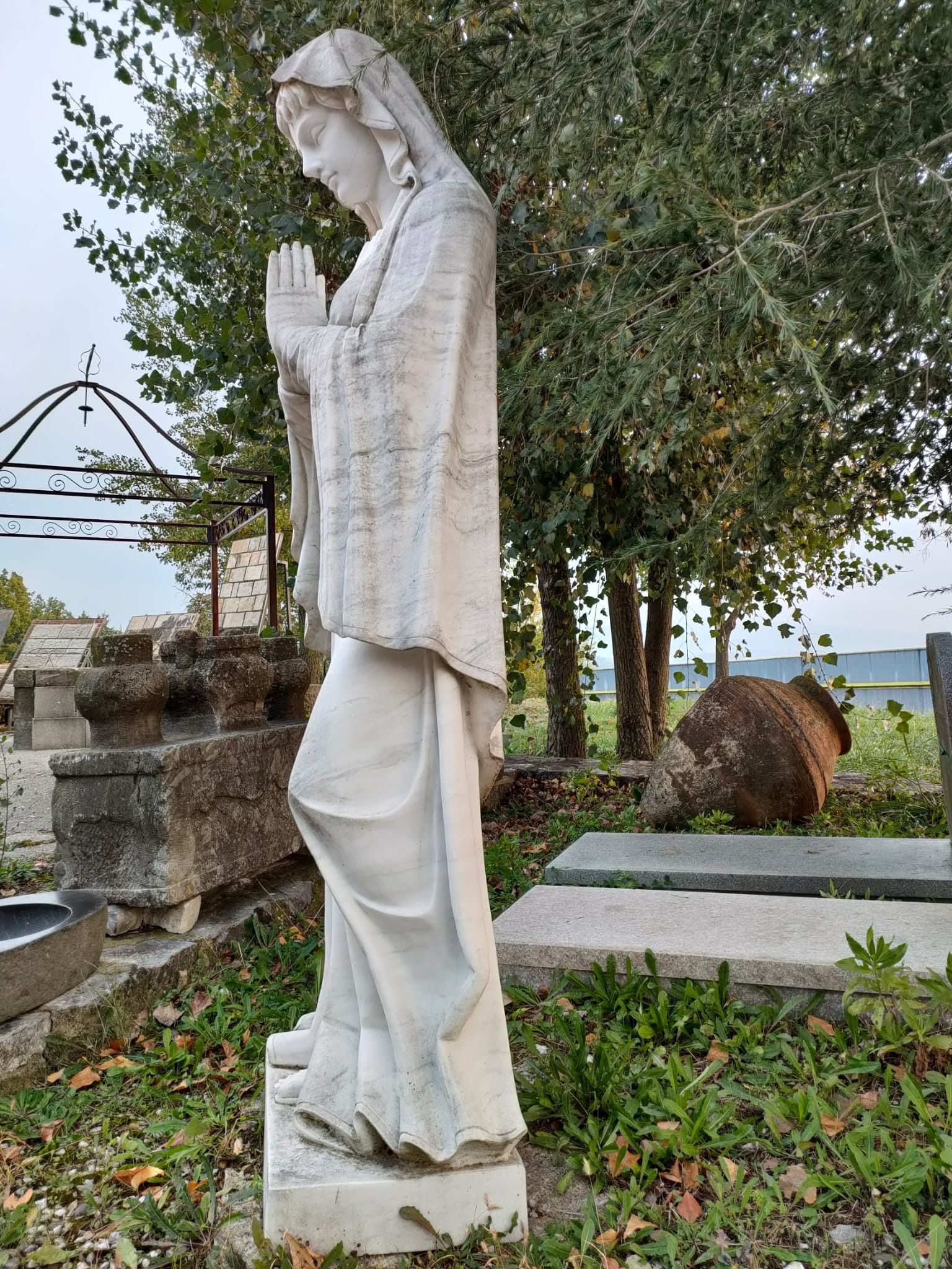 Una statua di una donna che prega in un cimitero.