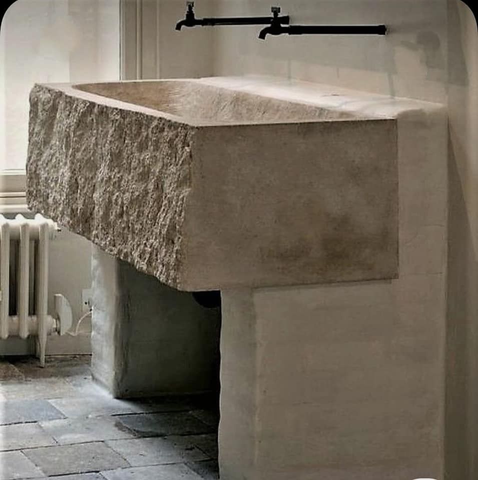 Un grande lavandino in pietra in un bagno con due rubinetti