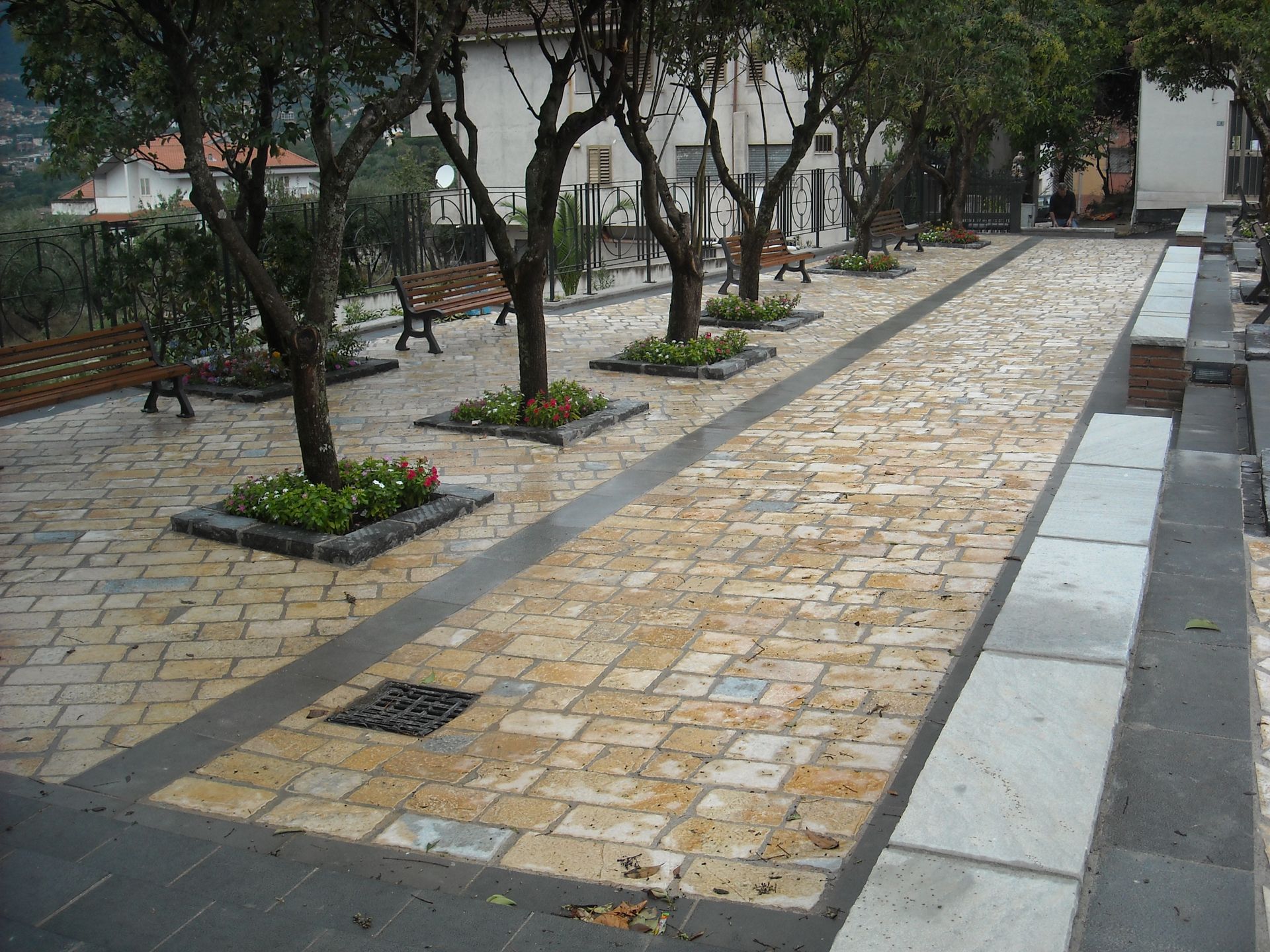 Una passerella di mattoni circondata da alberi e panchine