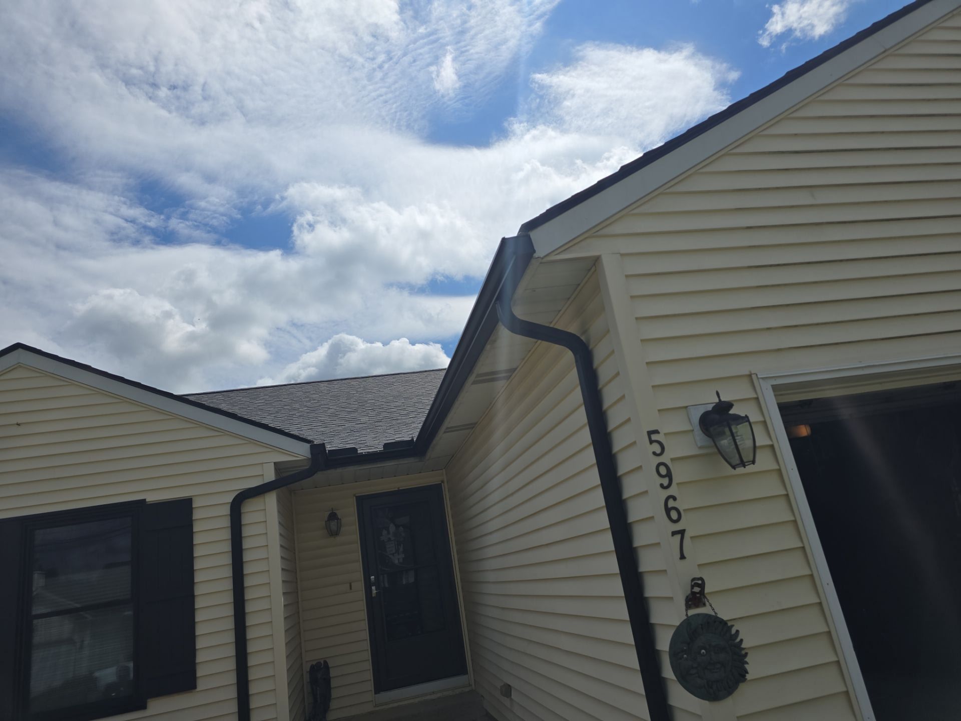 A man is fixing a gutter on the roof of a house.