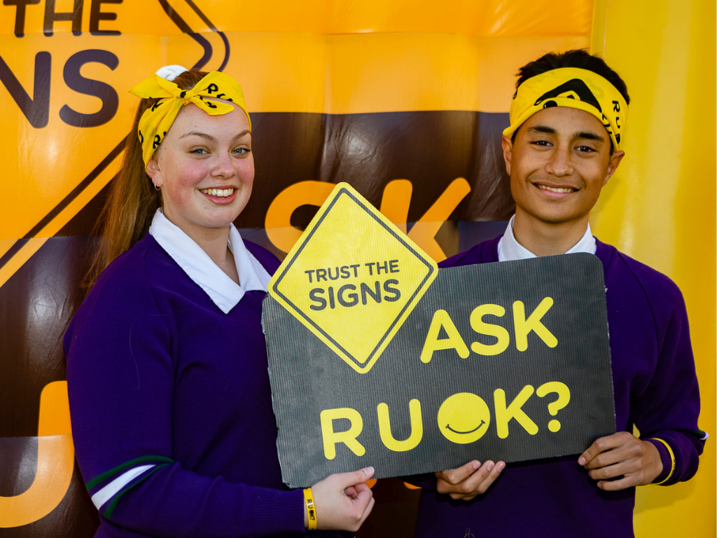 Male and female high school students holding R U OK? Sign