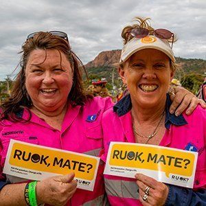 Two women smiling with R U OK? Signs