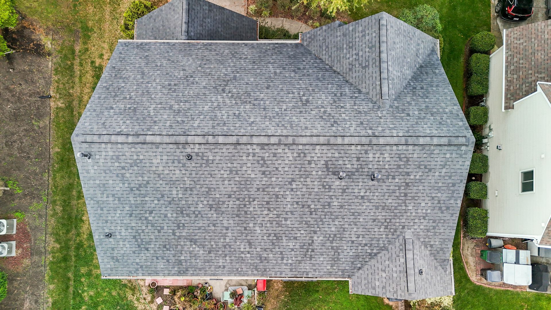 Aerial view of a house with a gray roof and surrounding green grass.