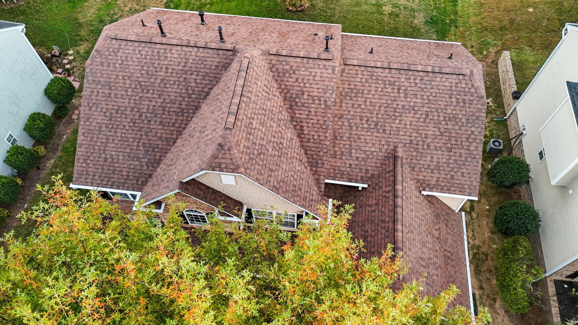 Brown shingled roof of a house with white trim, seen from an aerial view.