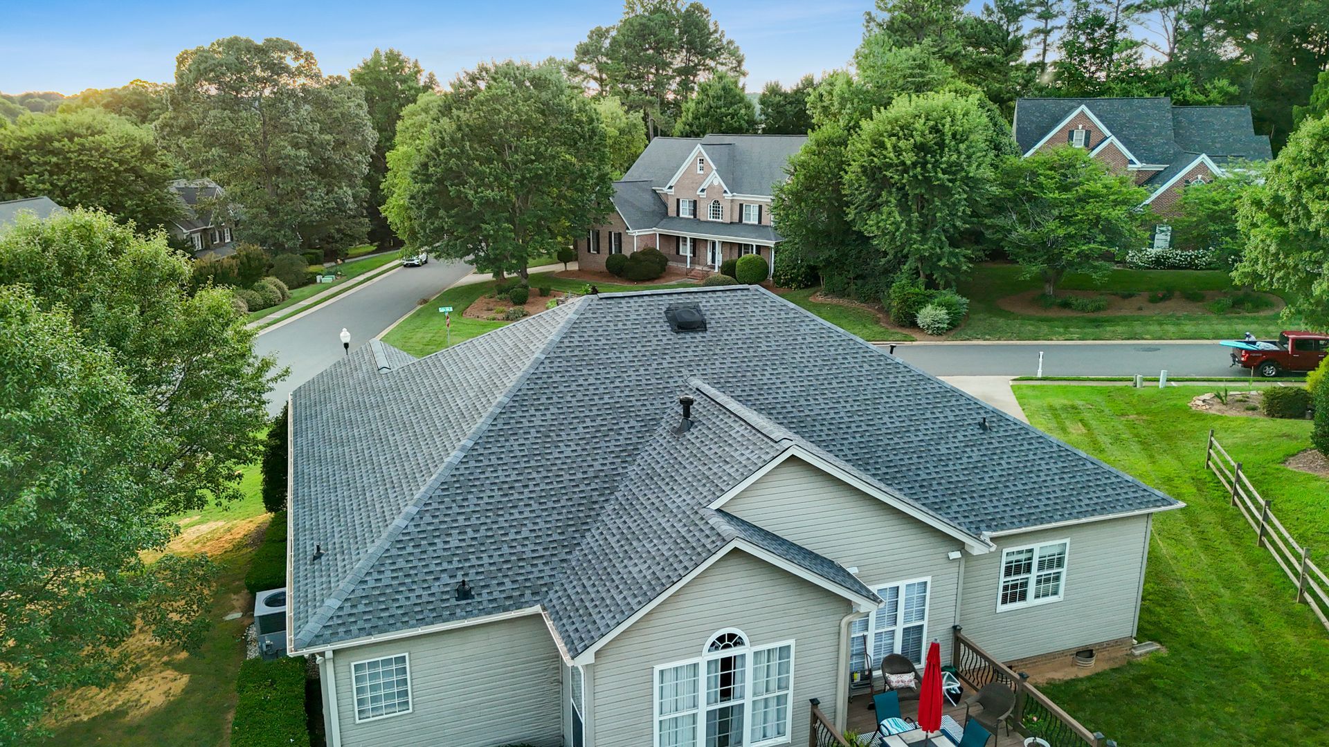 Gray roof of a house in a suburban neighborhood with trees.