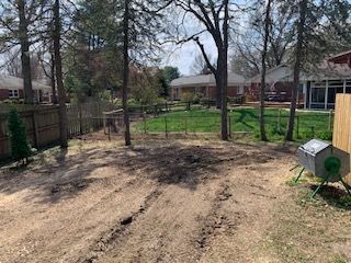 A dirt road leading to a house with trees in the background.
