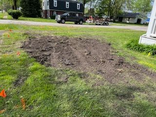 A truck is driving down a dirt road next to a house.