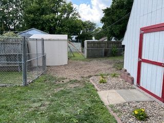 A backyard with a white shed and a red door.