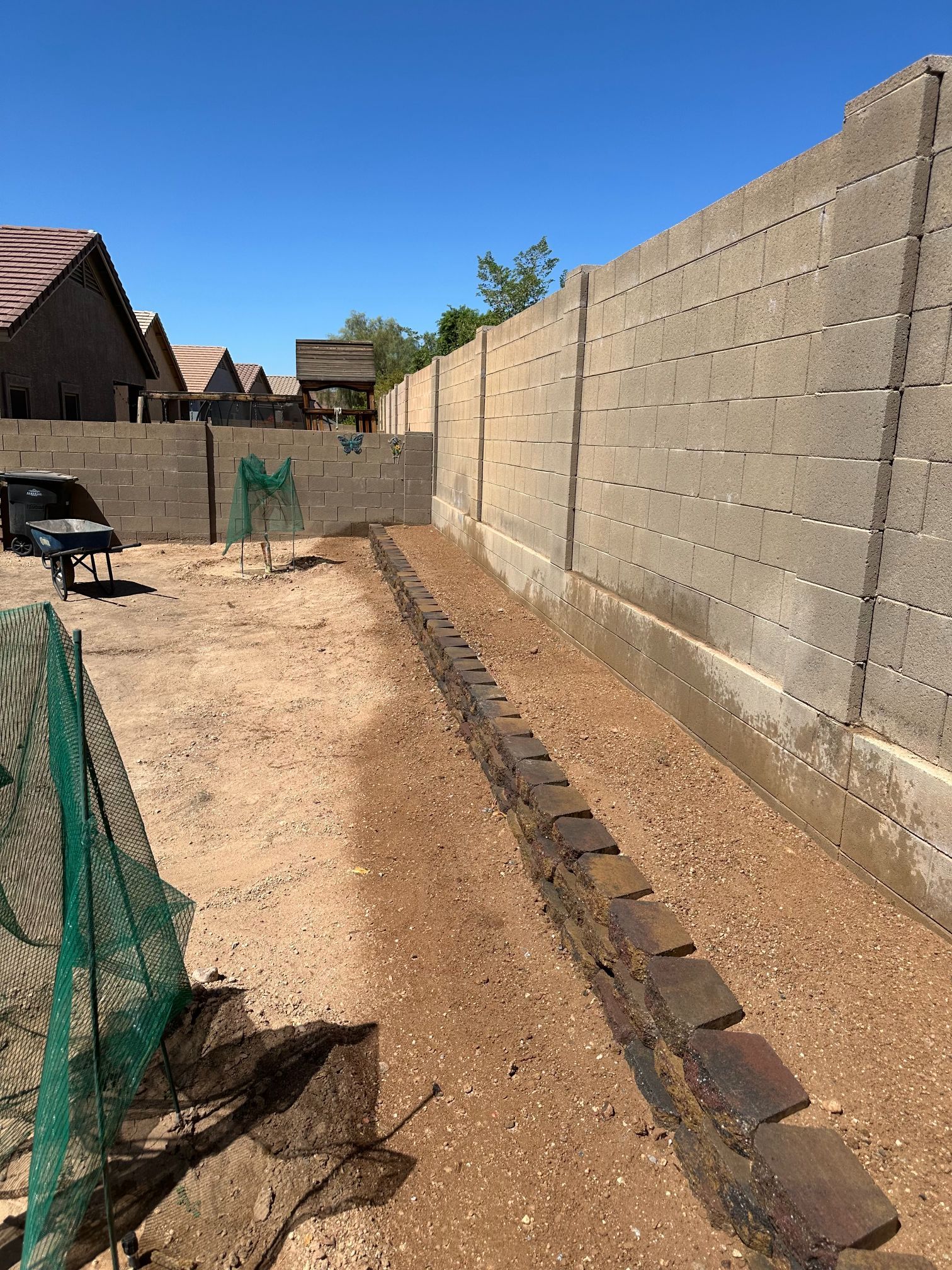 Dirt yard with a concrete wall, brown ground, and a black pickup truck in the background.