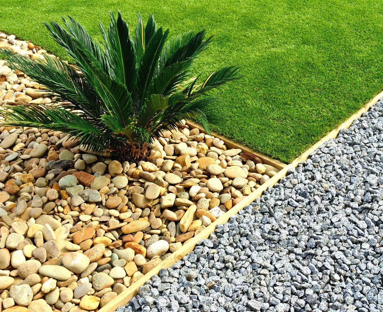 Gardener planting in a landscaped bed, with a variety of plants and black landscaping fabric.