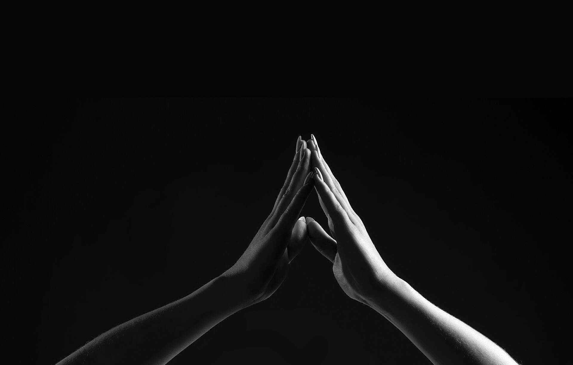 Two hands forming a triangular shape, touching fingertips, against a dark background.