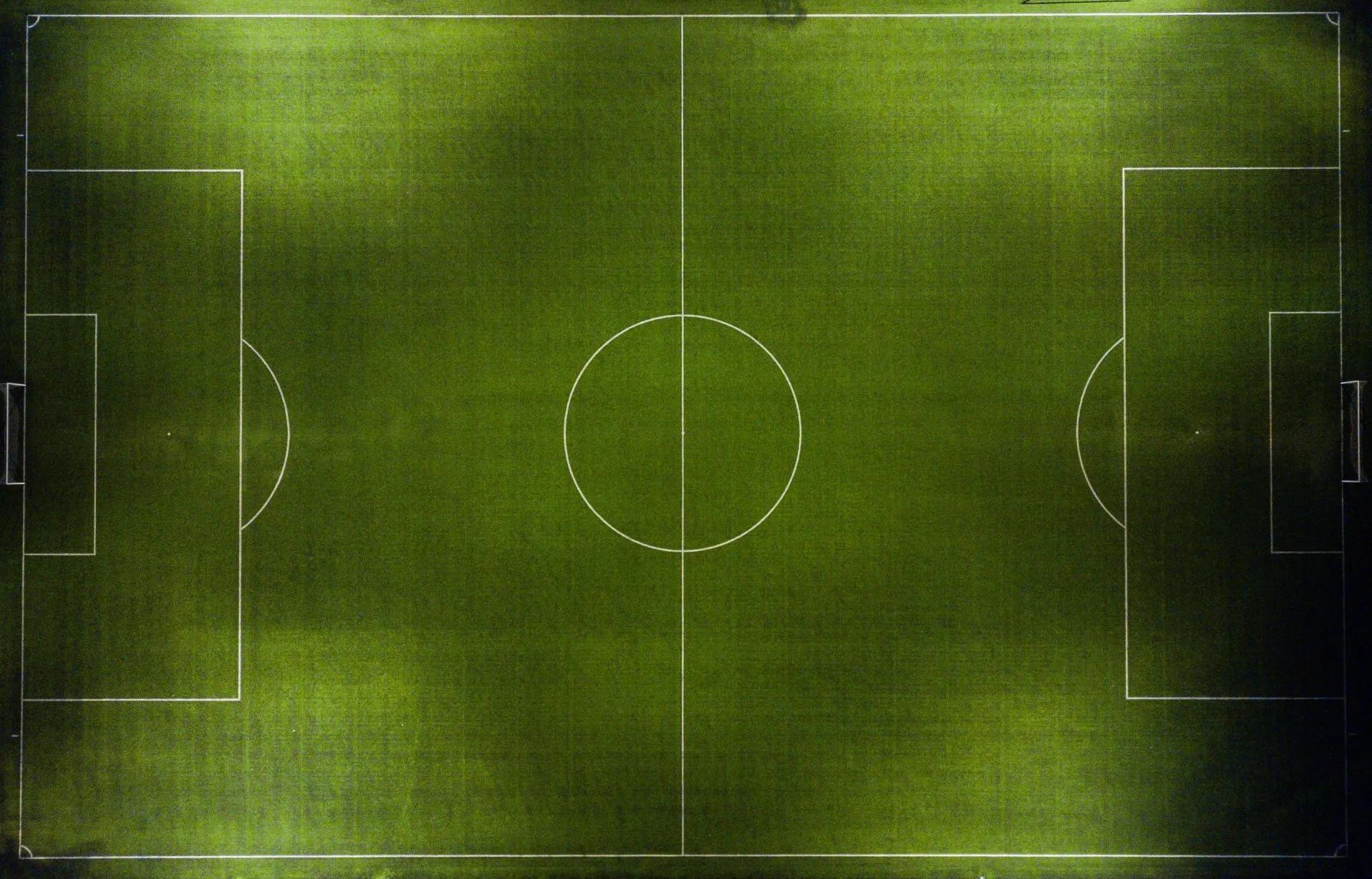 Overhead view of a soccer field with white markings on green grass.