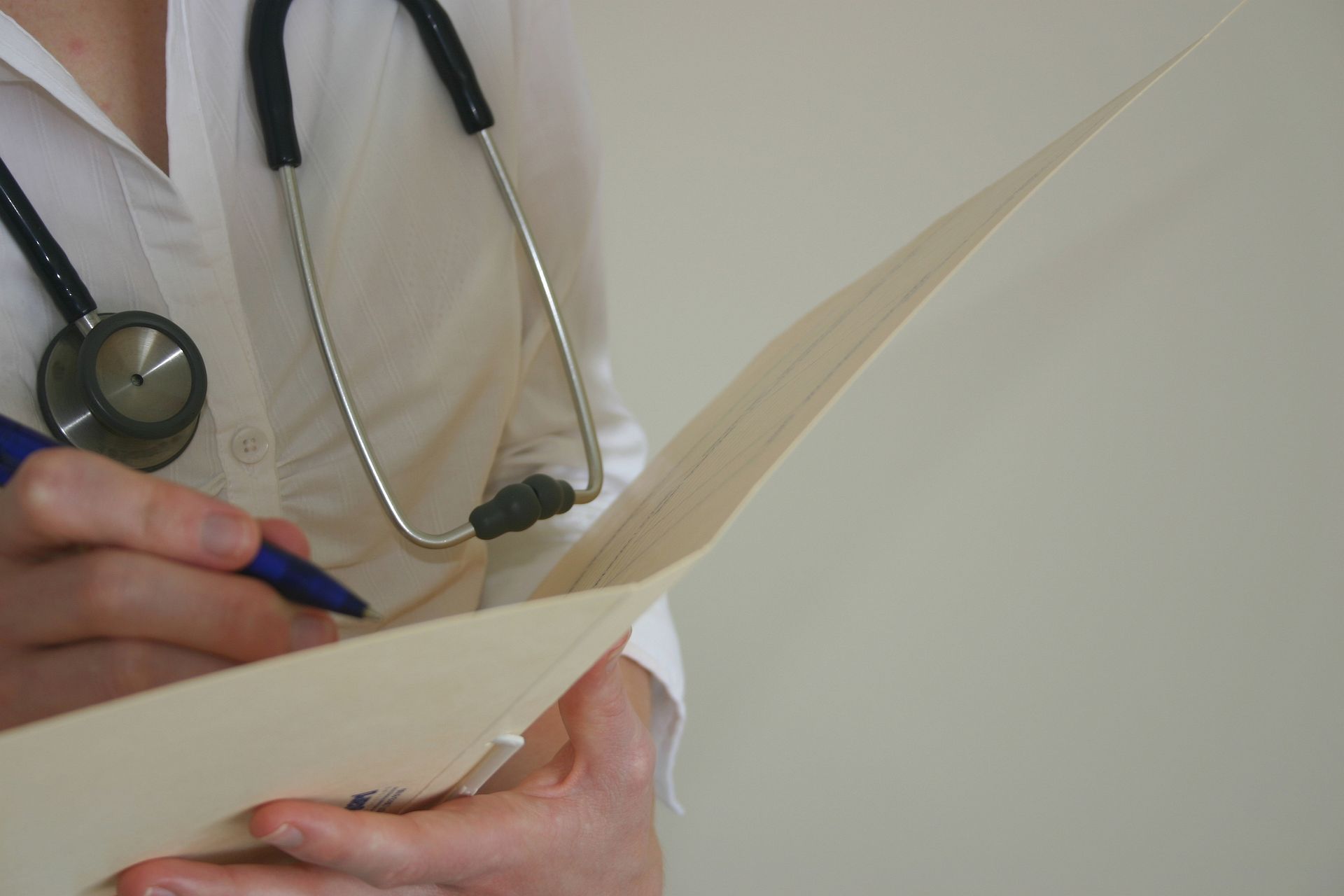 A doctor with a stethoscope around her neck is writing on a piece of paper.