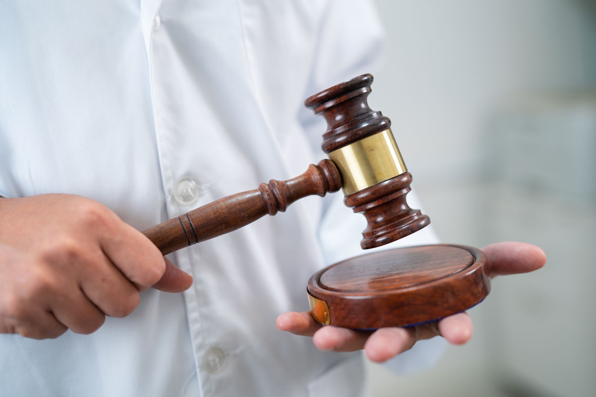 A judge is holding a wooden gavel in his hand.