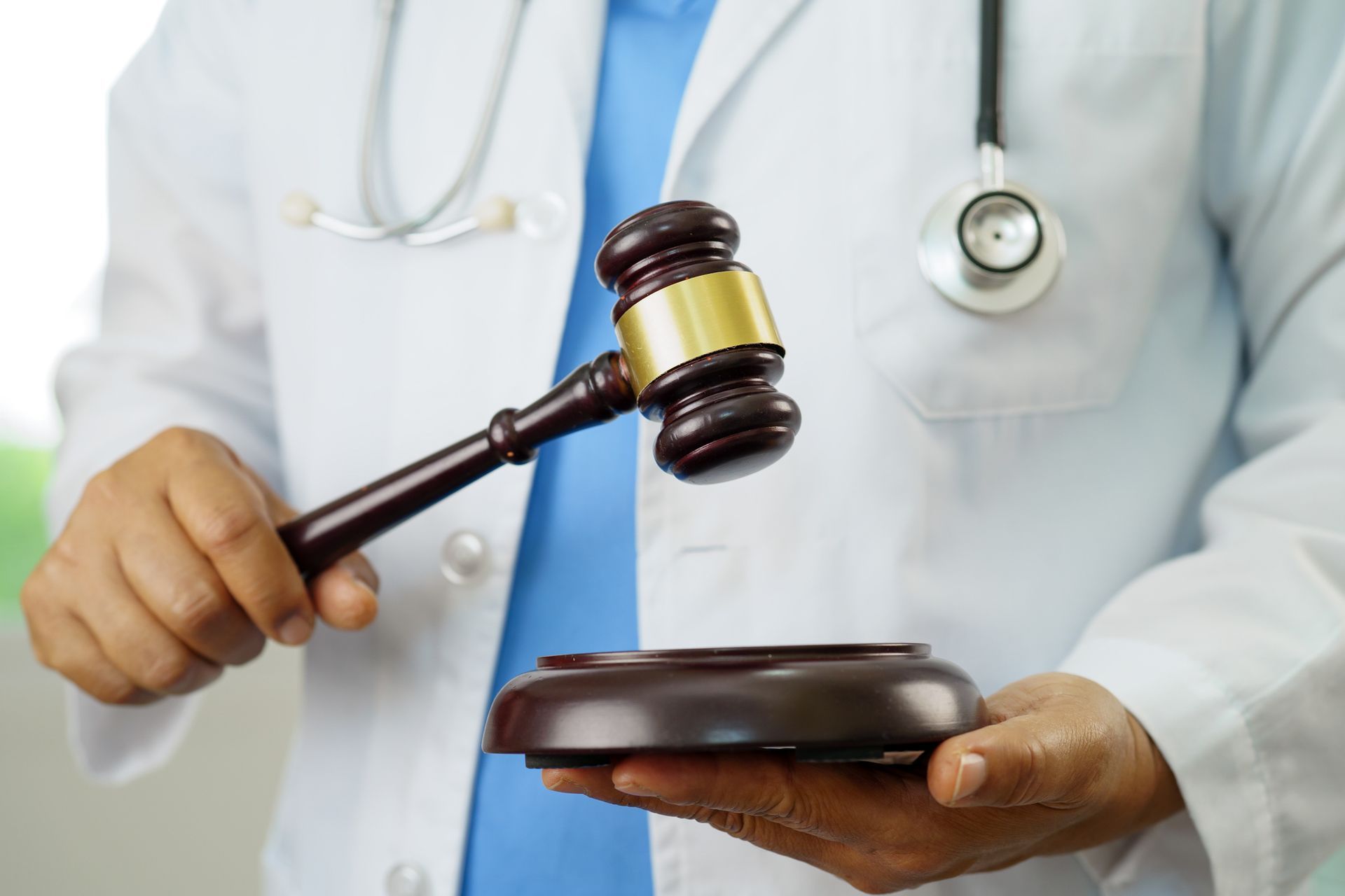 A doctor is holding a wooden gavel in his hands.