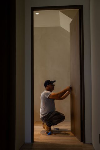 A man is kneeling down in front of a door.