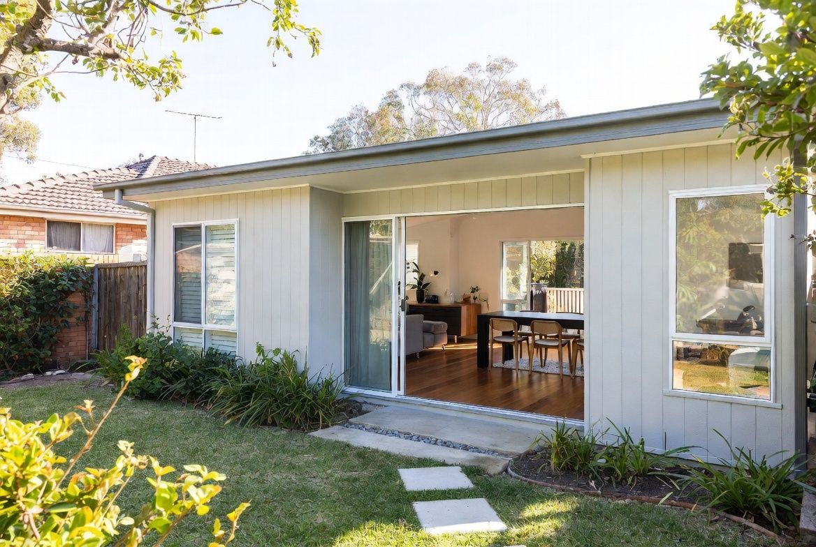 Modern gray house exterior with a small porch, sliding glass door, and front railing