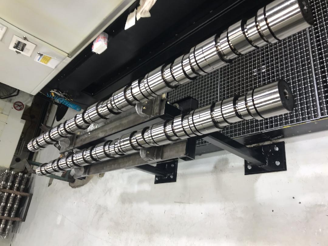 Two long, cylindrical metal rollers mounted on brackets, likely industrial equipment.