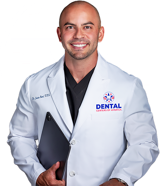 Smiling man in a white lab coat holding a tablet, with a dental logo on his coat.