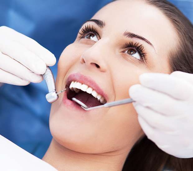 Woman at dentist's office with mouth open, receiving dental exam.