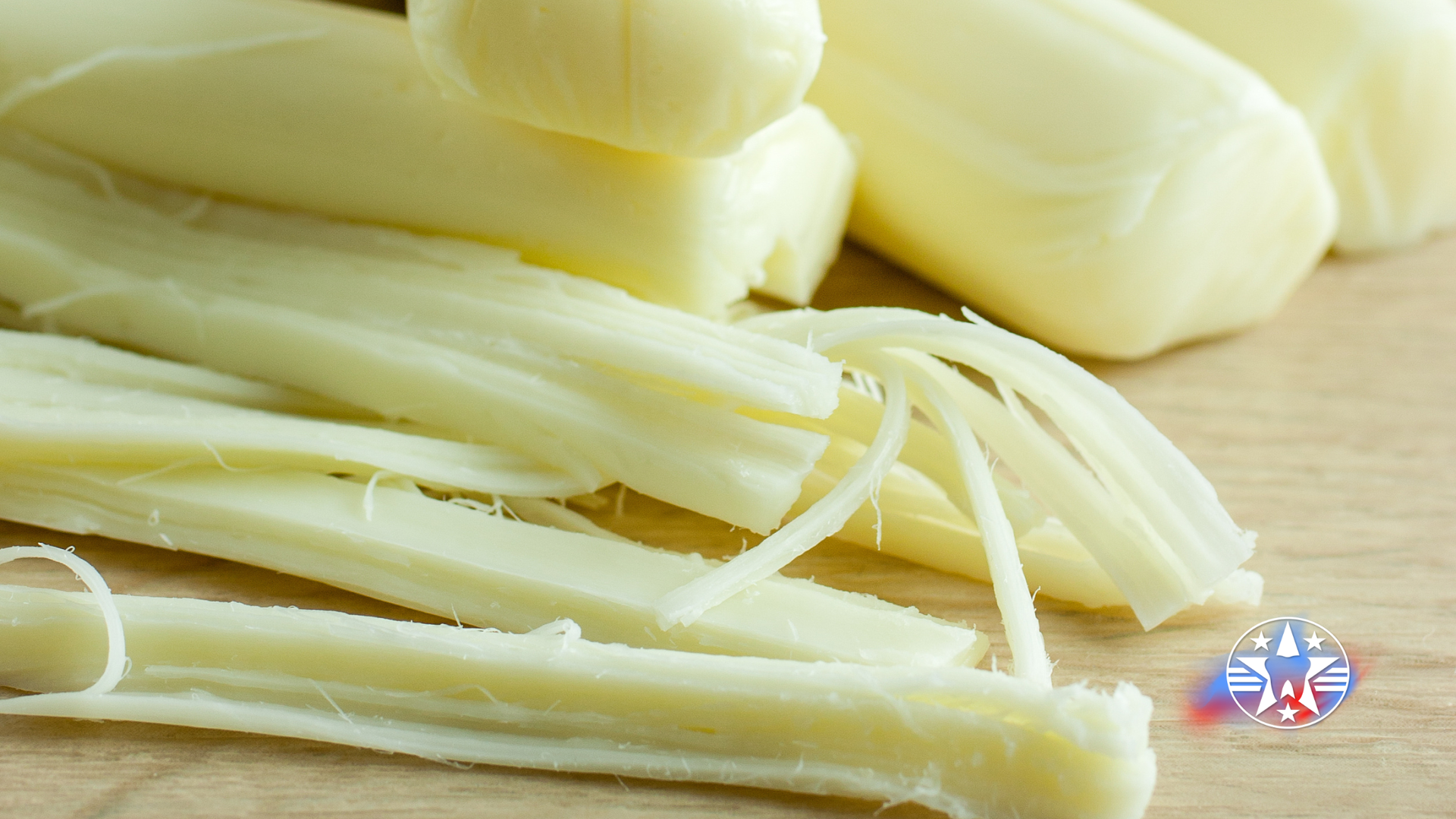 String cheese, some pulled apart, on a wooden surface.