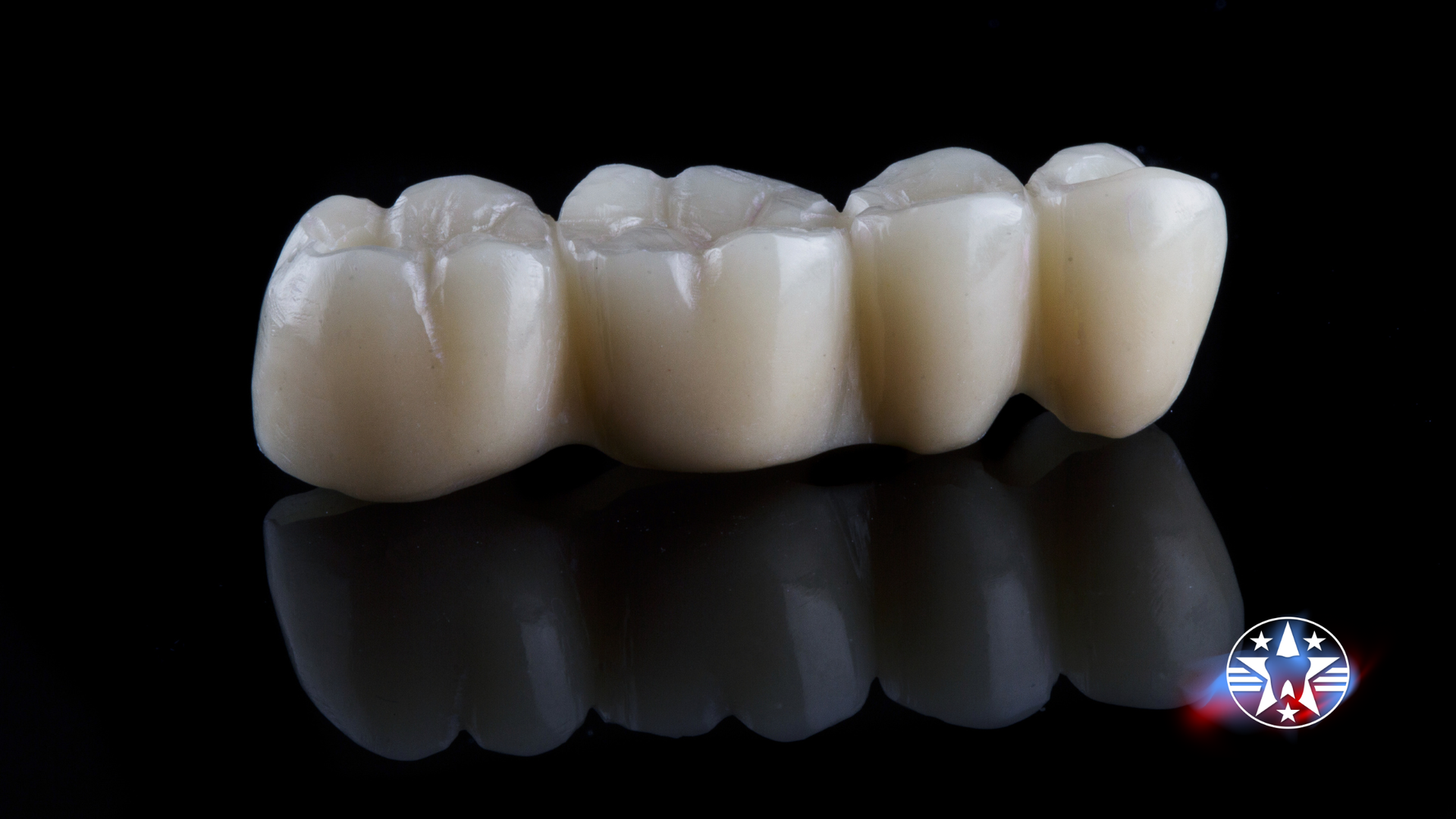 Dental bridge, three porcelain teeth, light cream color, against a black background.