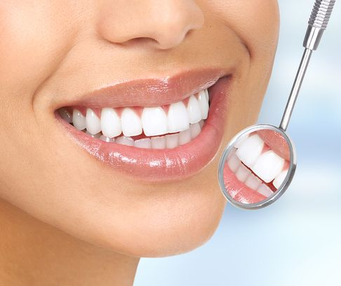Woman smiling, showing perfect white teeth, dental mirror reflecting teeth.
