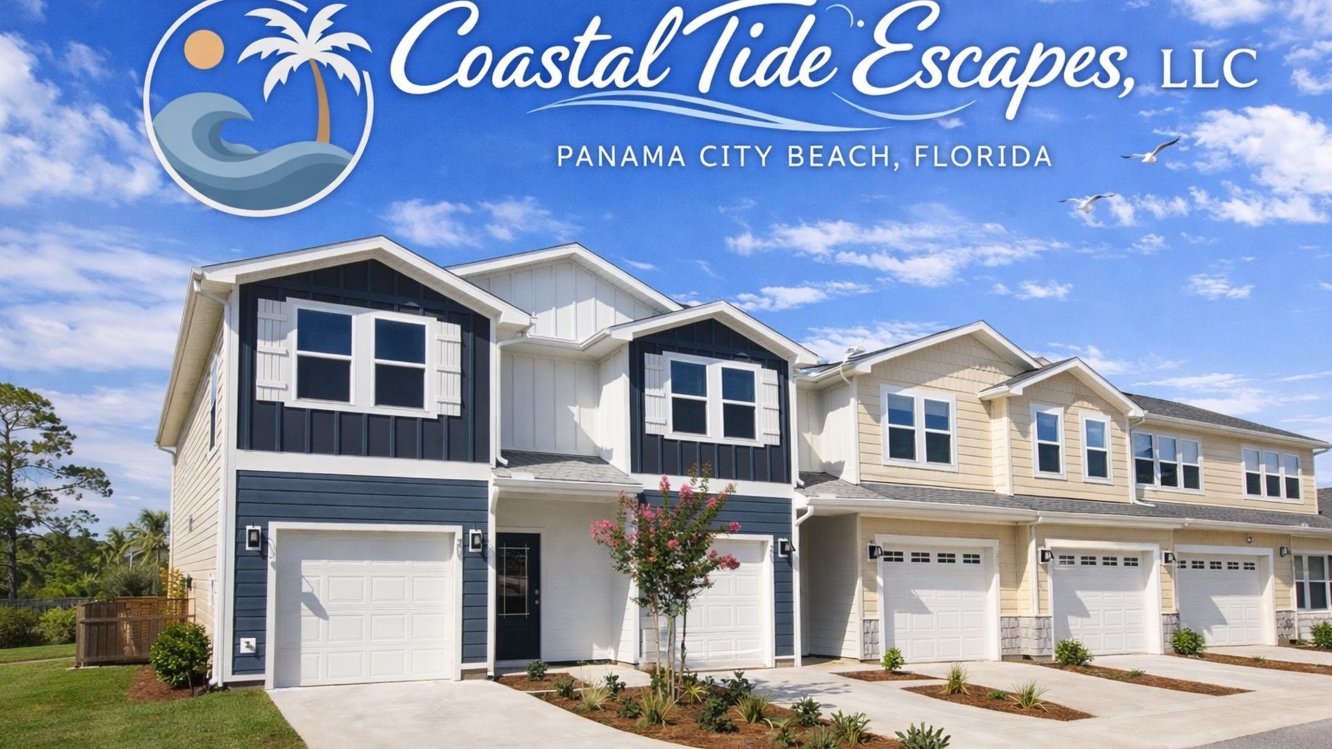 Row of modern townhouses with white siding and dark blue accents, garages and landscaped front yards.