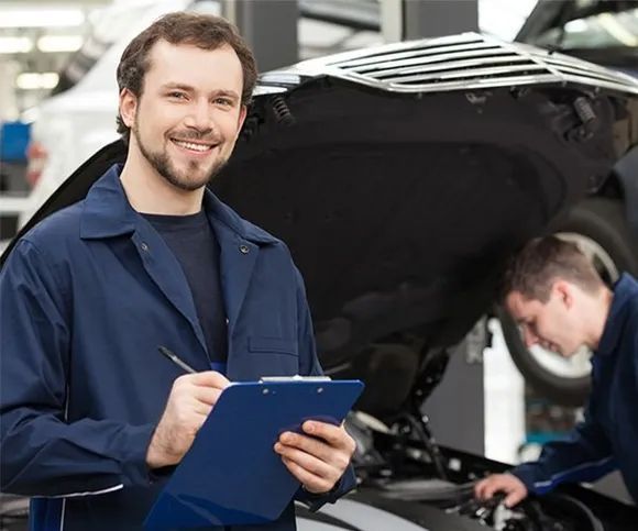 A Man Is Holding A Clipboard In Front Of A Car While Another Man Works On It — All Engine Repairs in South Murwillumbah, NSW