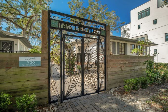 A wrought iron gate is leading to a house.