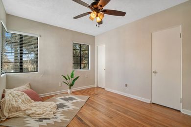 An empty bedroom with hardwood floors , a ceiling fan , and a window.