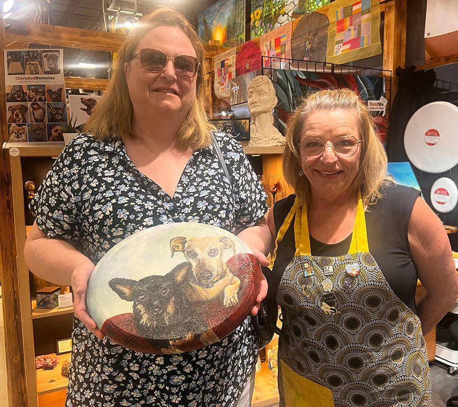 Two women are holding a plate with a picture of a dog on it.