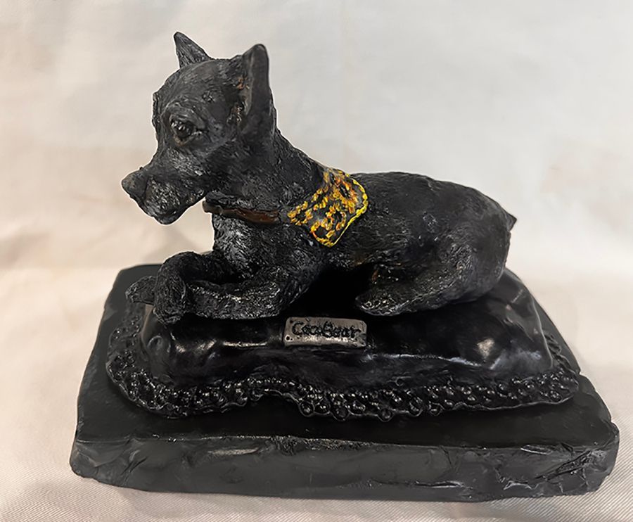 A black statue of a dog with a gold collar
