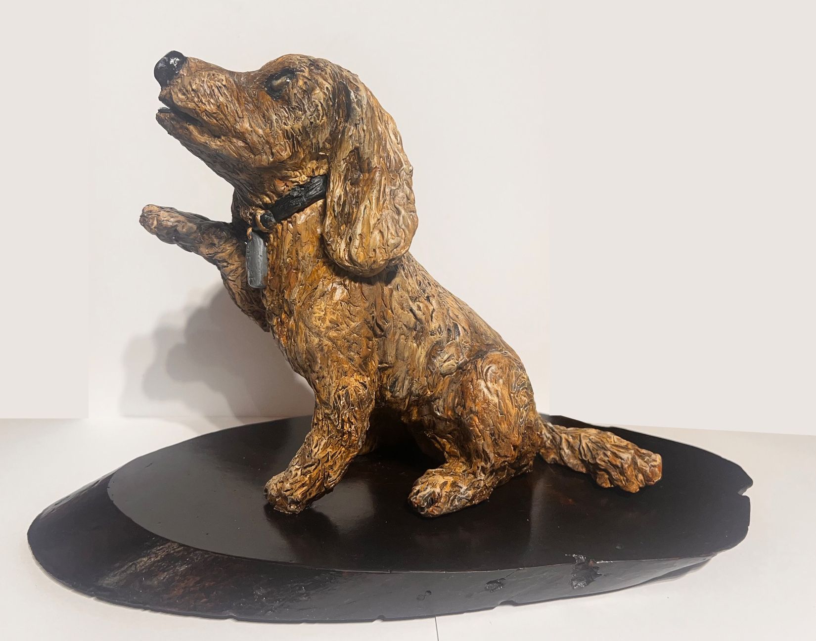 A statue of a dachshund sitting on a black plate