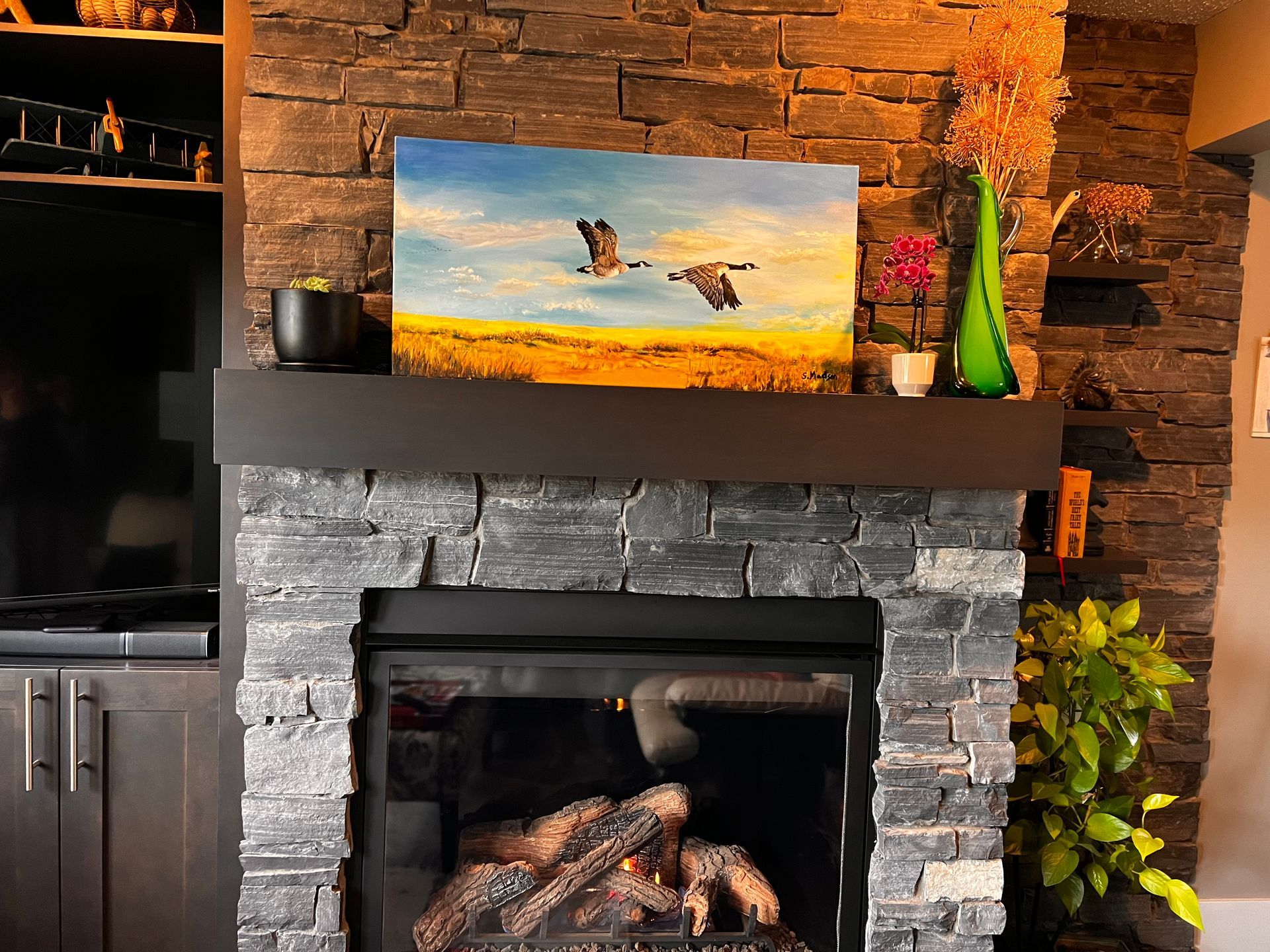 A living room with a fireplace and a painting on the mantle