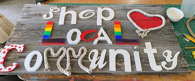 A wooden sign that says `` shop local community '' is sitting on a table.