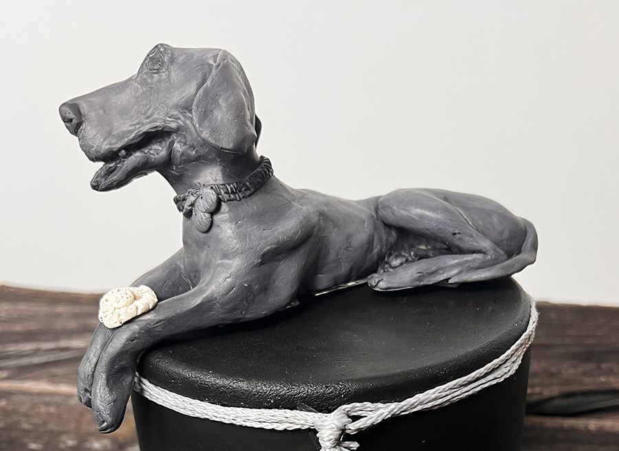 A statue of a dog laying on top of a black box
