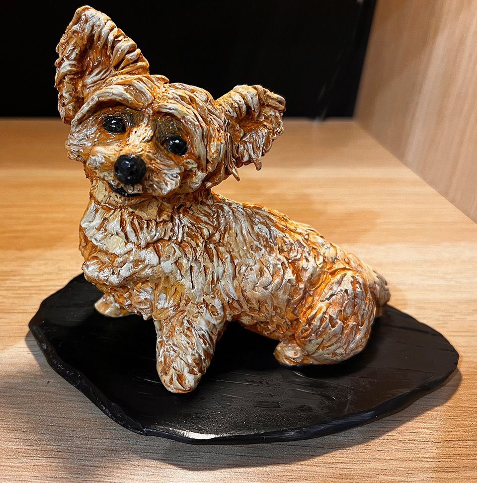 A small statue of a dog is sitting on a wooden table