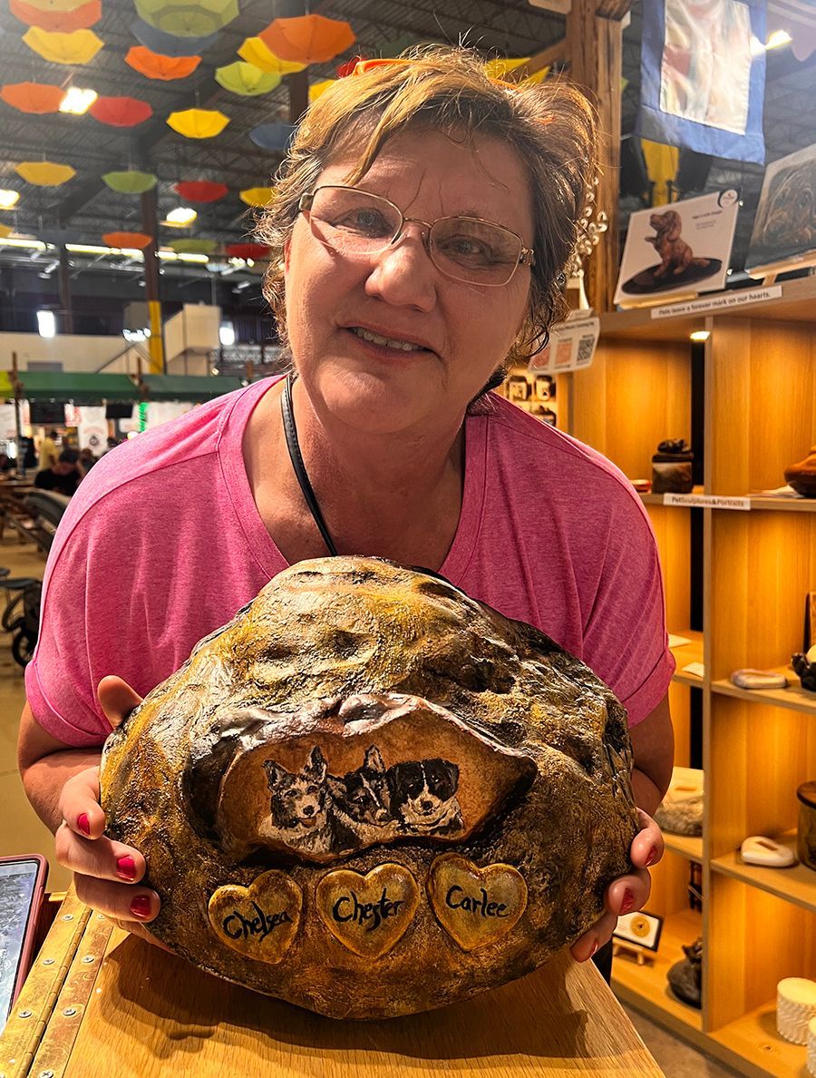 A woman in a pink shirt is holding a large piece of bread